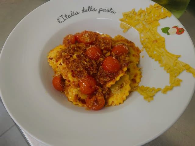 Hausgemachte Ravioli mit Kirschtomaten auf einem Teller mit Italien-Motiv