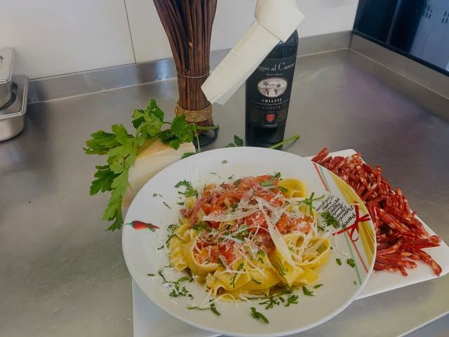 Tagliatelle mit Lachs und Parmesan, daneben eine Flasche Chianti